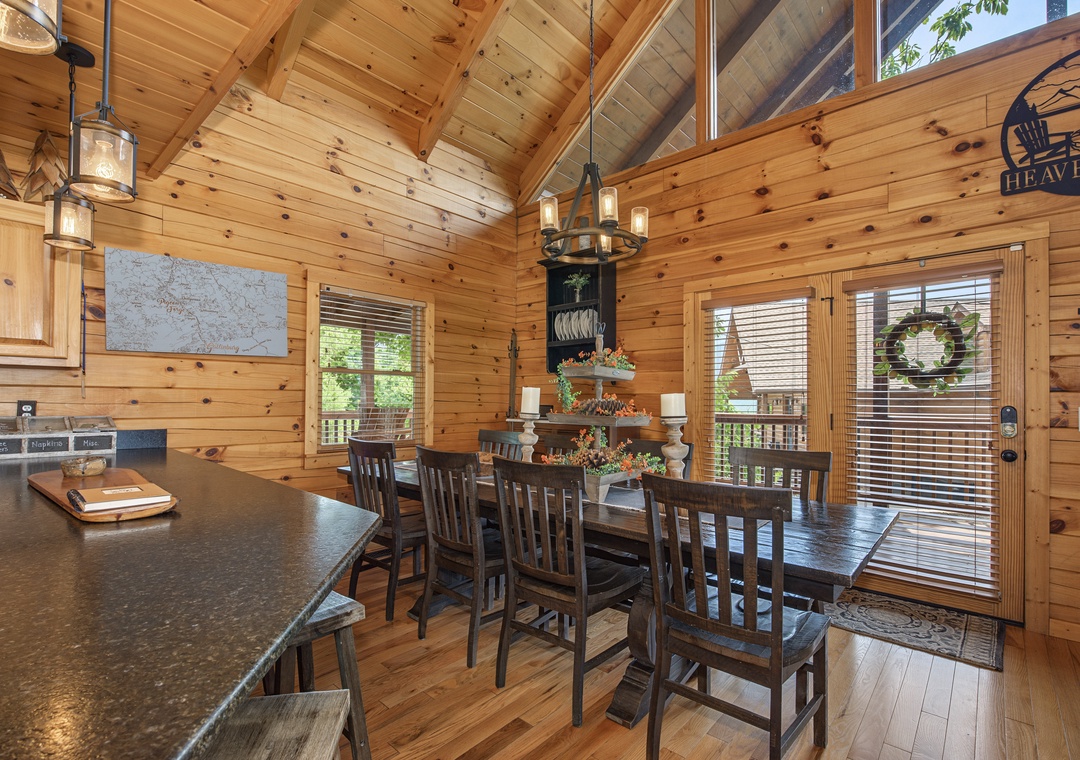 Gather around the rustic dining table under vaulted ceilings, where warm wood surrounds you and natural light pours through windows framing peaceful forest views.