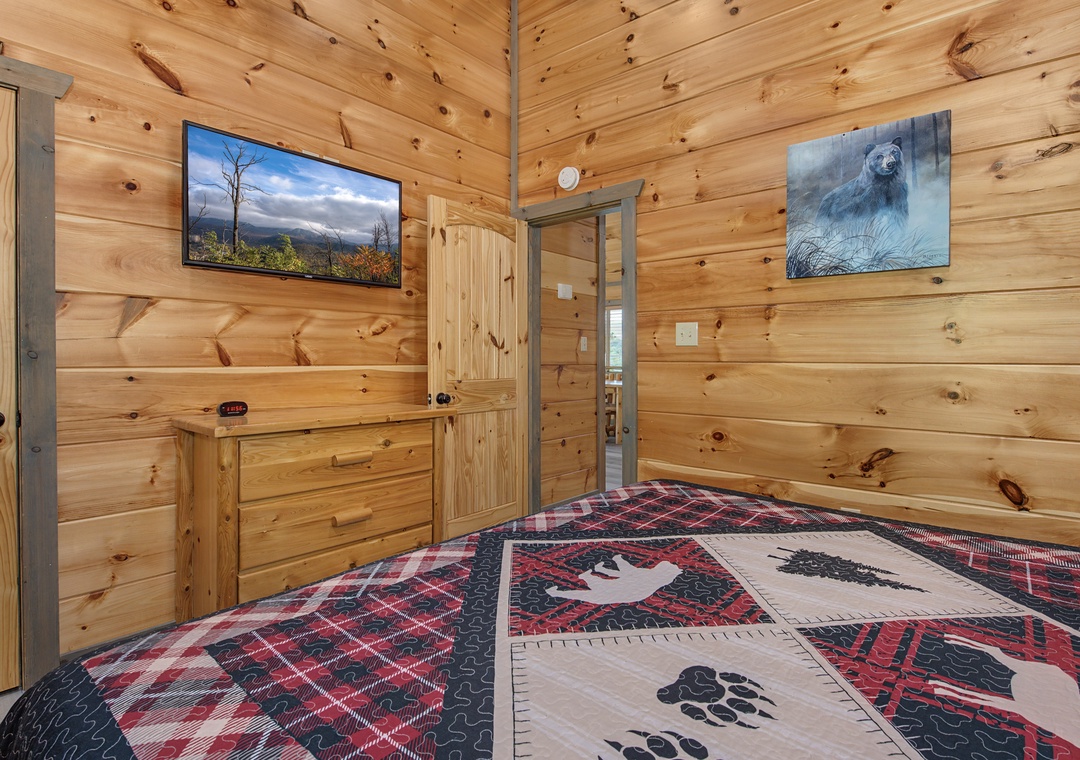 Cozy up in your rustic cabin bedroom with warm knotted pine walls, a plush bed dressed in wilderness-themed linens, and your own flat-screen TV for mountain movie nights.