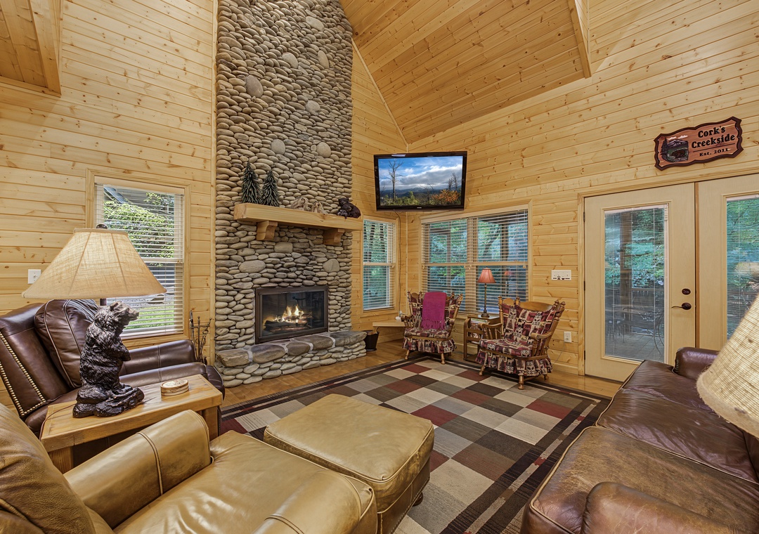 Sink into plush leather seating by your glowing stone fireplace, where tall cathedral ceilings and warm pine walls create your perfect mountain retreat.