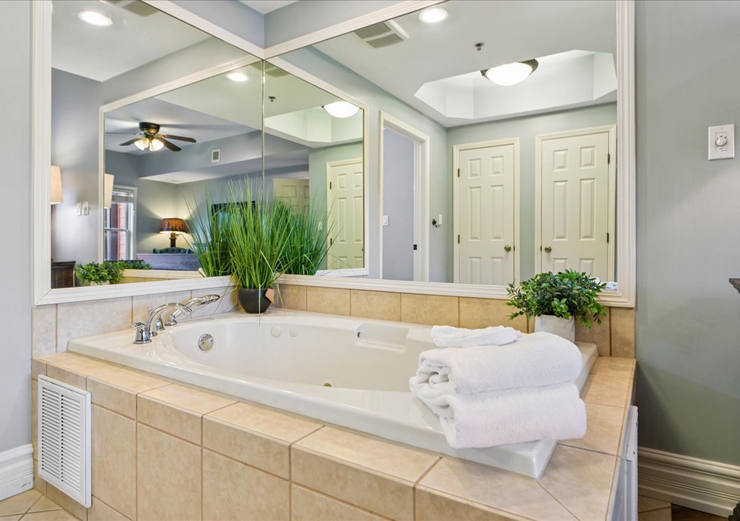 Sink into your private jetted tub surrounded by elegant tile work and fresh greenery, with plush towels waiting for your ultimate relaxation.