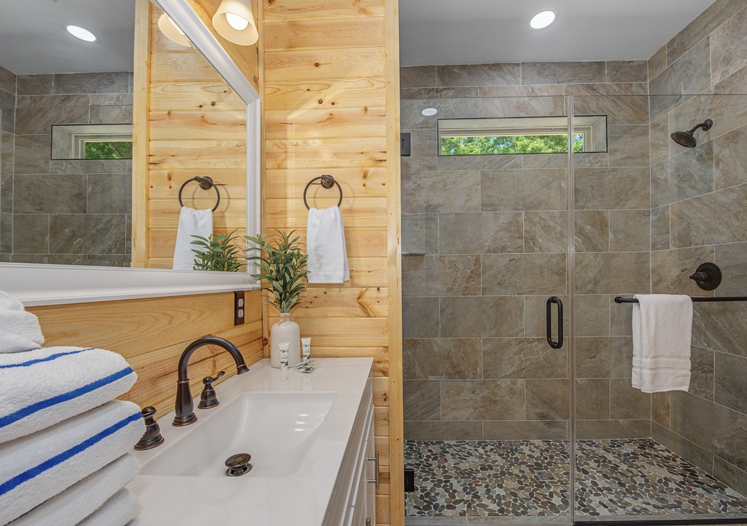 Freshen up in this modern bathroom featuring a sleek vanity with ample counter space and a spacious walk-in shower with natural stone accents. Plush towels and thoughtful touches make your morning routine feel luxurious.