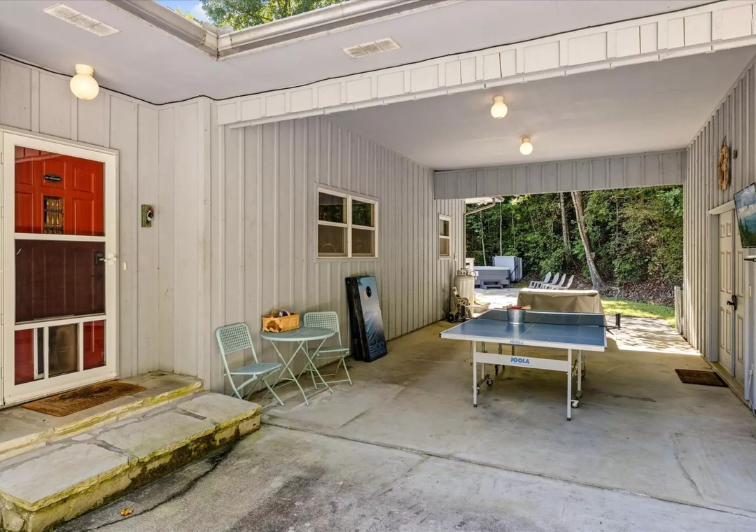 Your private covered patio features ping pong for family fun, with seating and a hot tub beyond—perfect for active days and relaxing evenings.