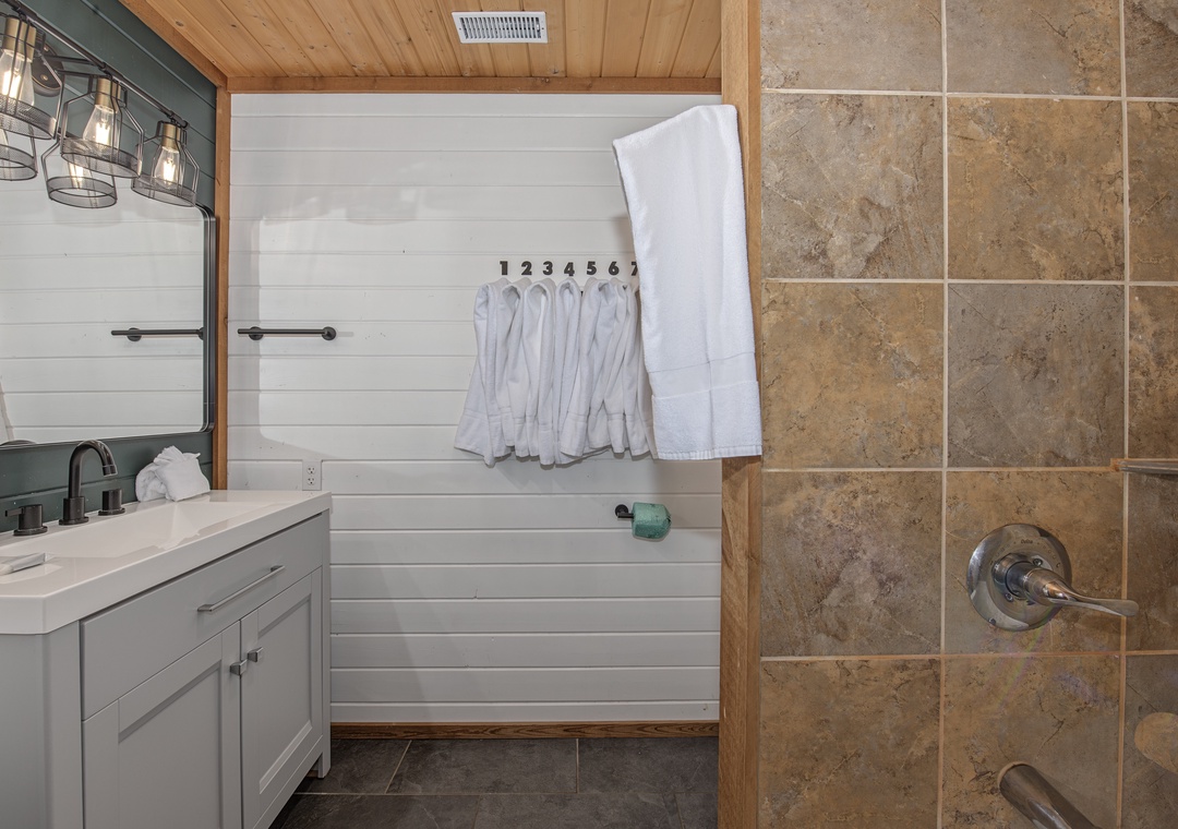 Step into your private bathroom, where rustic charm meets modern comfort—fresh towels await and a spacious tiled shower invites you to unwind after each day's adventures.