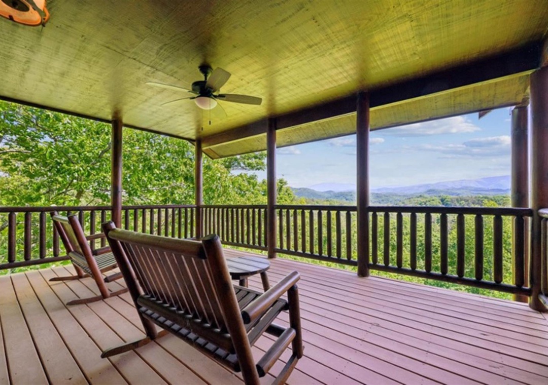 A spacious covered deck with rocking chairs perfectly frames sweeping mountain views through lush forest canopy—an ideal spot to unwind and soak in nature's beauty.