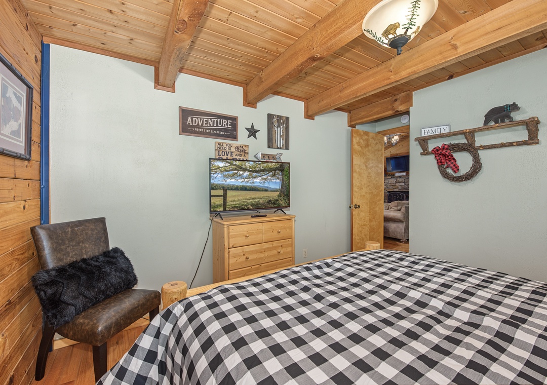 Your cozy mountain bedroom awaits with warm wooden beams, rustic charm, and thoughtful touches like the black-and-white plaid bedding. Unwind after a day of adventure in this inviting retreat.