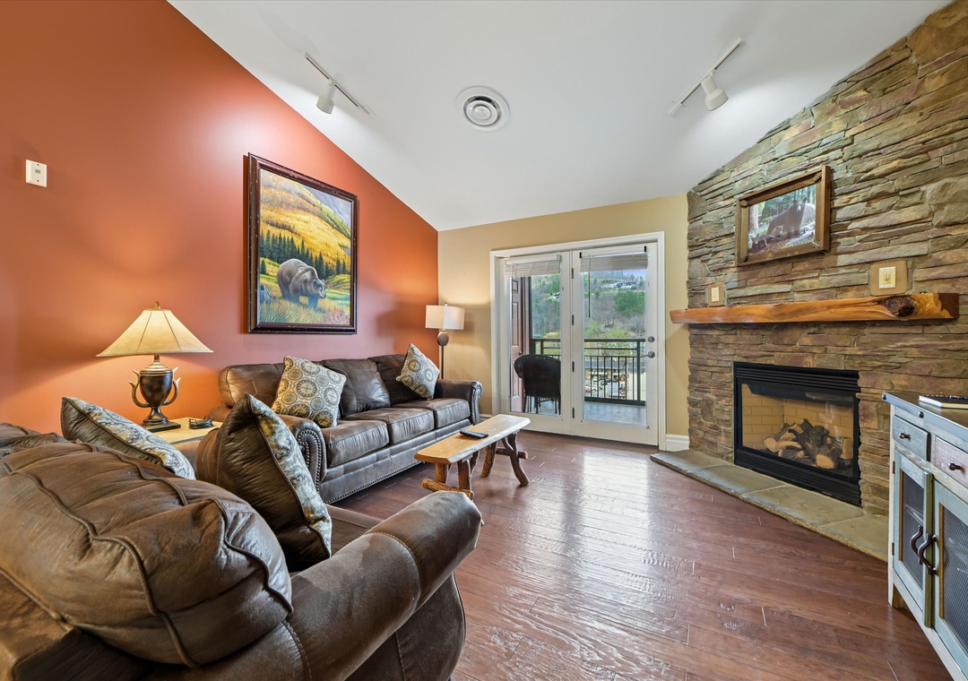 Unwind in your cozy living room with a crackling fireplace, leather seating, and doors opening to your private balcony.