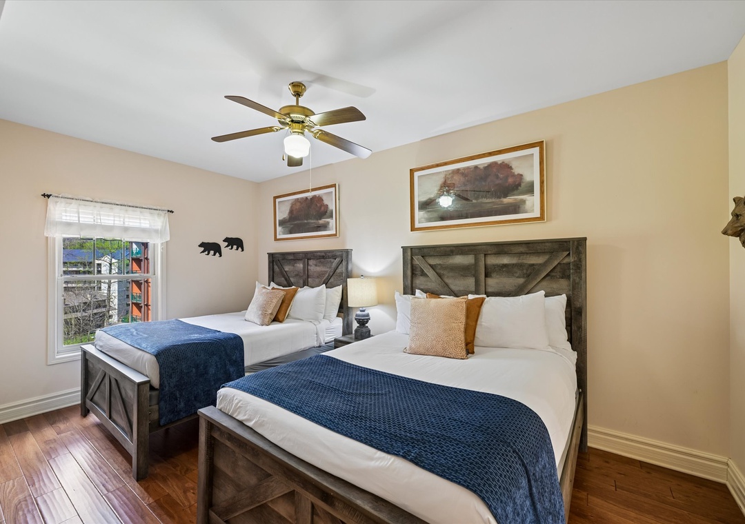 Your cozy twin bedroom features rustic beds, warm decor, and a ceiling fan for comfort.