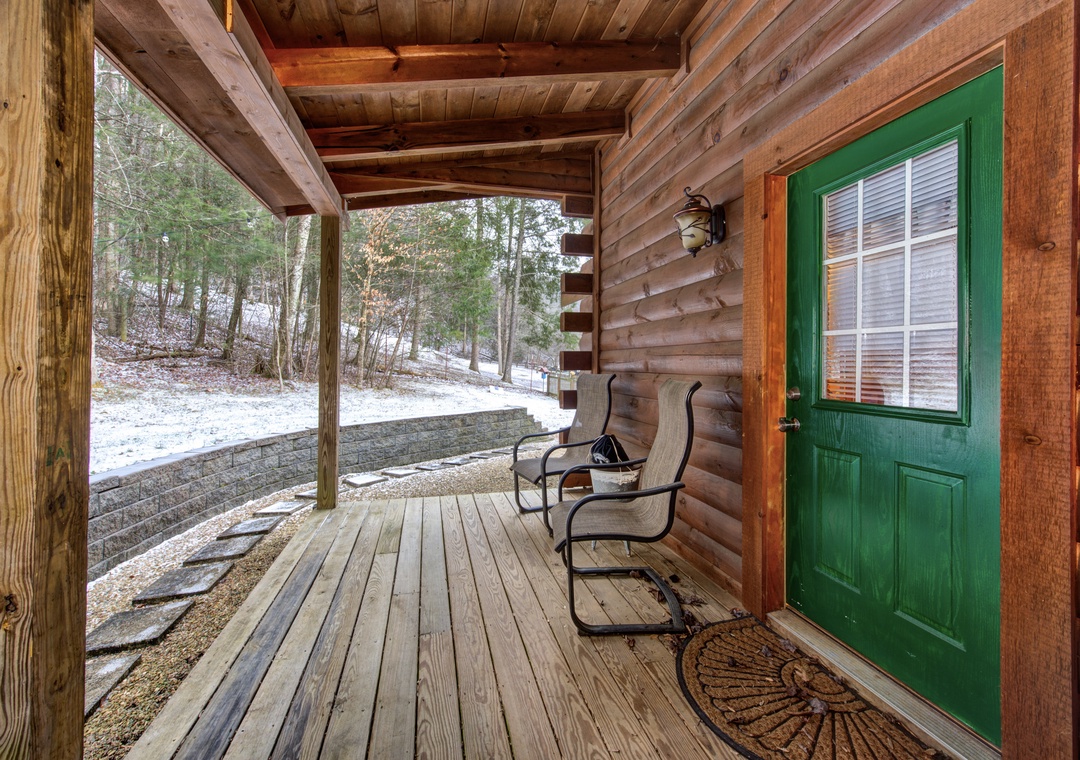 Step onto your rustic covered porch where forest views and cozy chairs await your morning coffee moments.