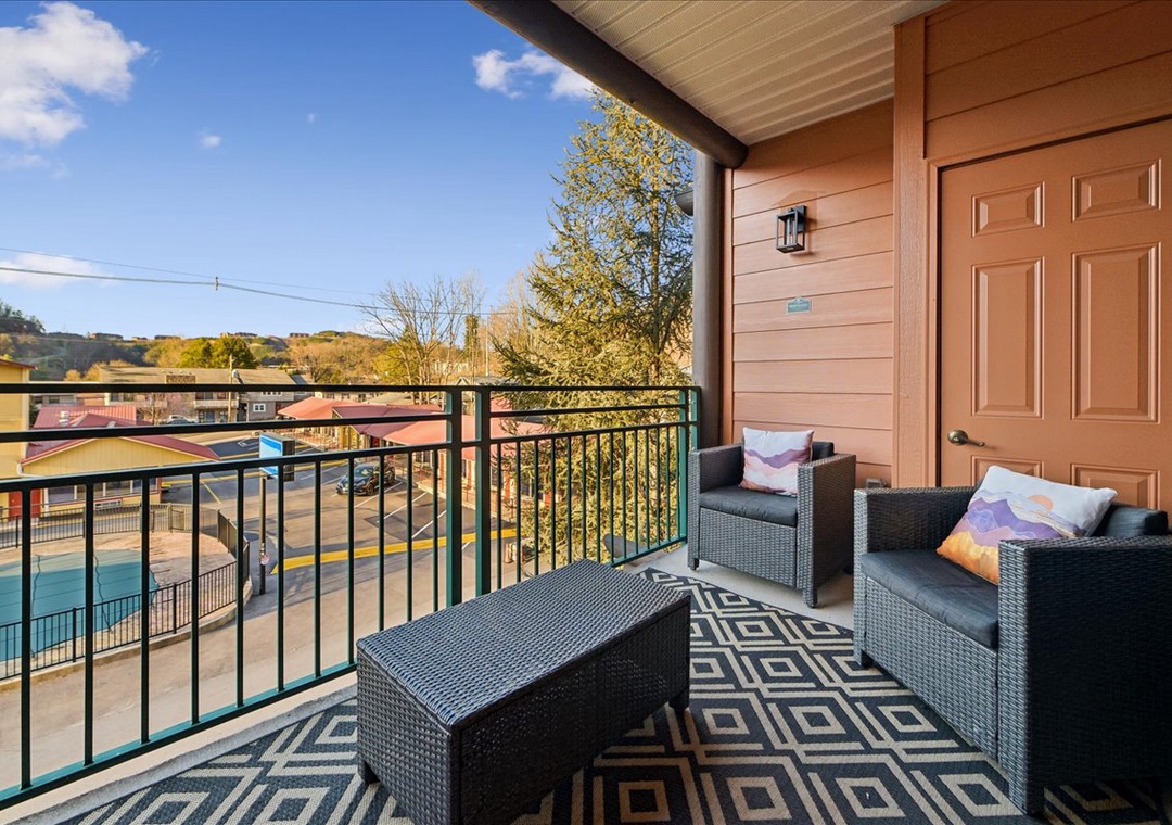 Relax on your private balcony with comfortable seating while taking in peaceful neighborhood views and distant hills.