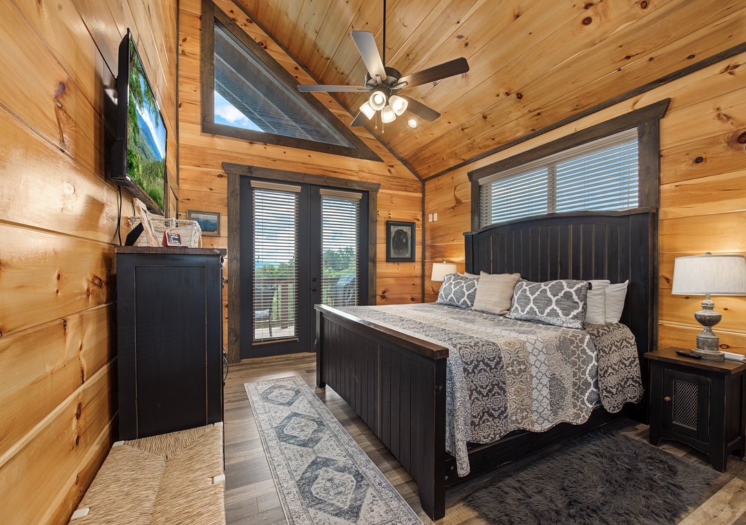 Unwind in your private bedroom, where rustic wood planks meet modern comfort. Sink into the plush bed after a day of exploring, enjoying ceiling fan breezes and peaceful outdoor views through your door.