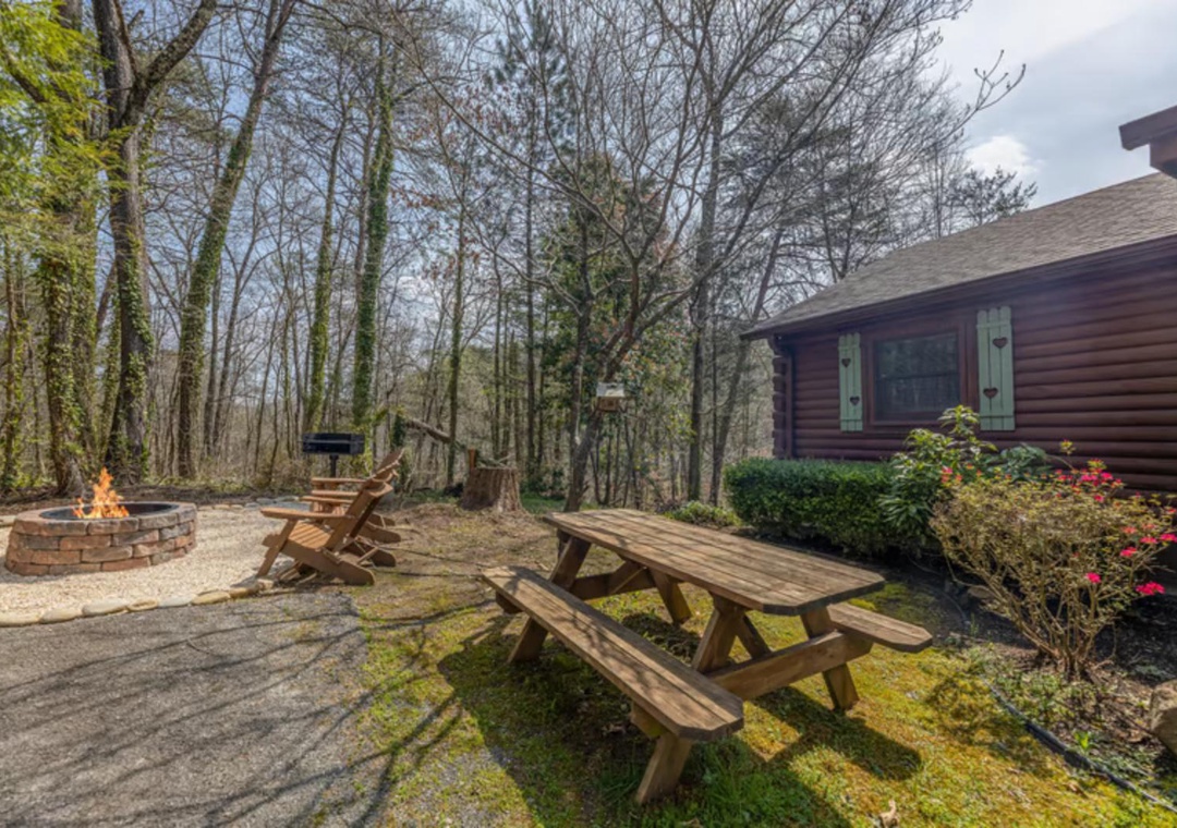 This charming cabin nestled among towering trees offers your own private outdoor retreat. Gather around the stone fire pit, enjoy meals at the picnic table, and soak in the peaceful woodland setting surrounding your home away from home.