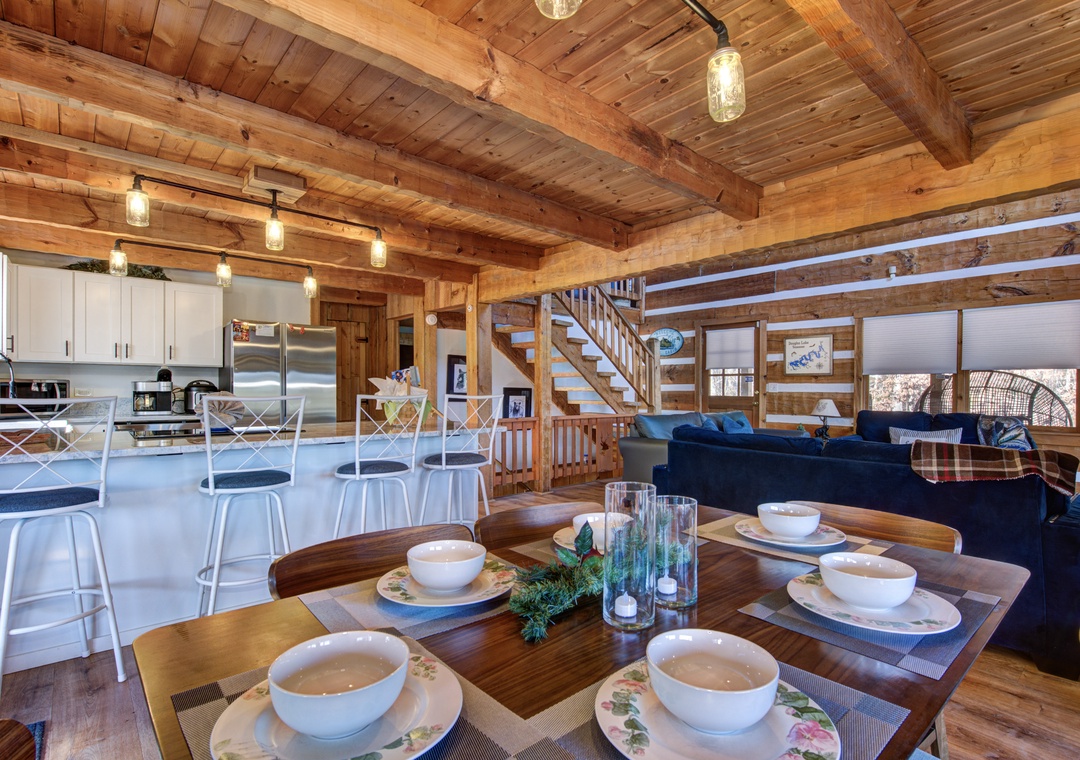 Gather around this rustic dining table where exposed beams and warm wood create your perfect mountain retreat atmosphere.