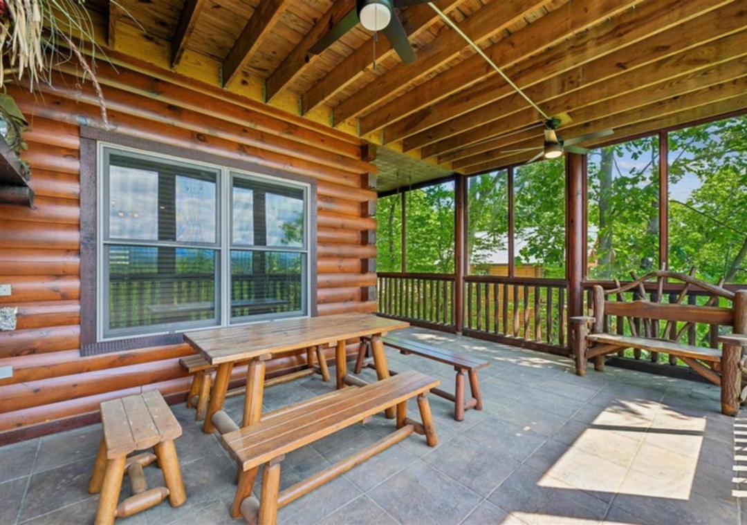 Your covered porch offers rustic charm with handcrafted wooden seating, surrounded by lush greenery and natural light streaming through screened walls—a perfect spot to relax and breathe in the fresh air.
