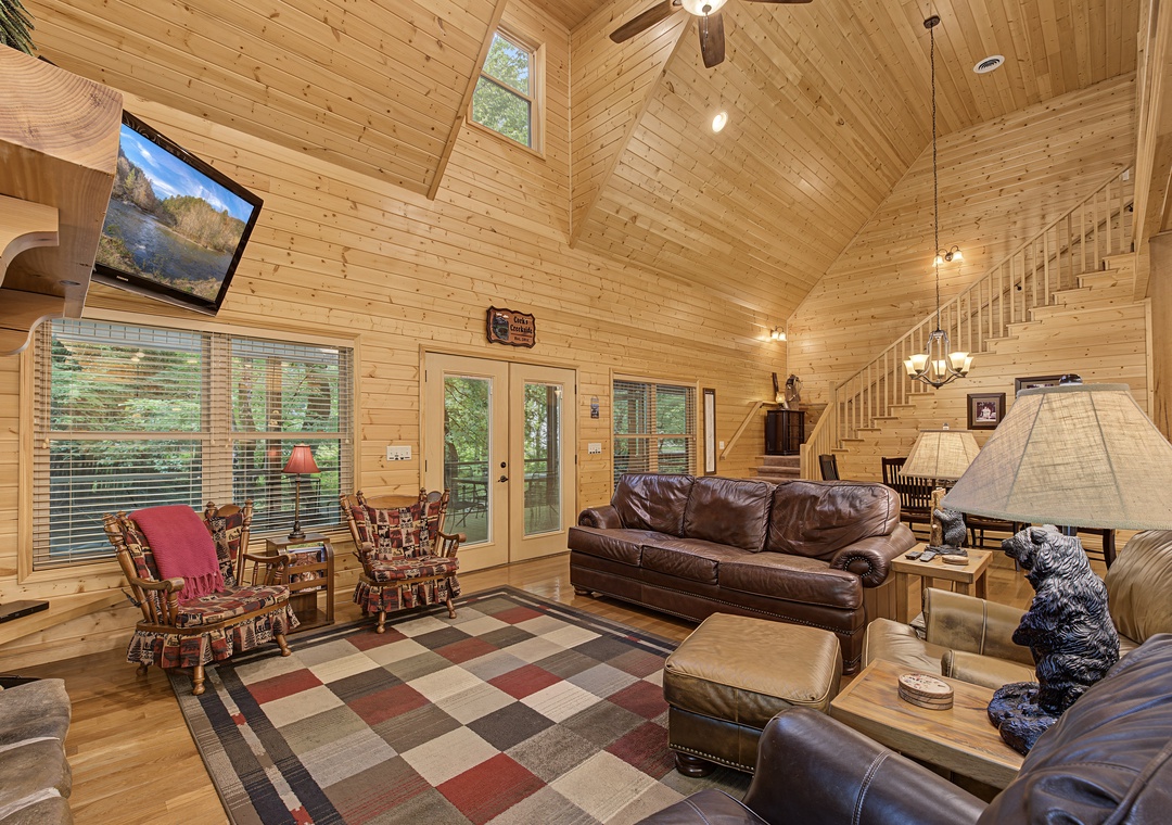 Sink into plush leather sofas beneath soaring vaulted ceilings, where warm wood tones and natural light create your perfect mountain retreat sanctuary.