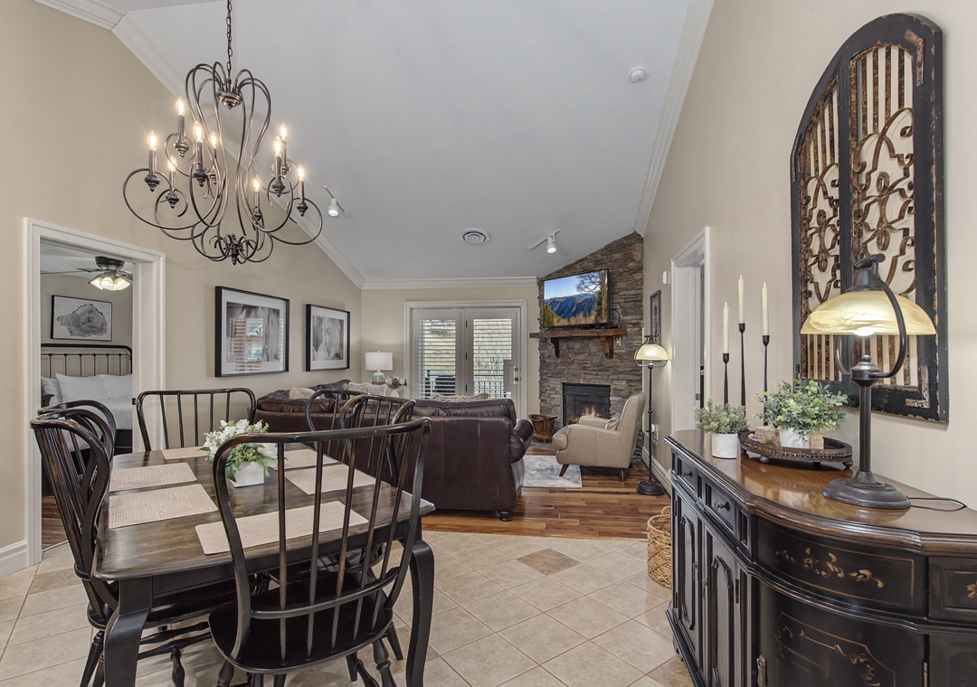 Gather around your elegant dining table while the stone fireplace creates a cozy ambiance in this beautifully appointed living space.