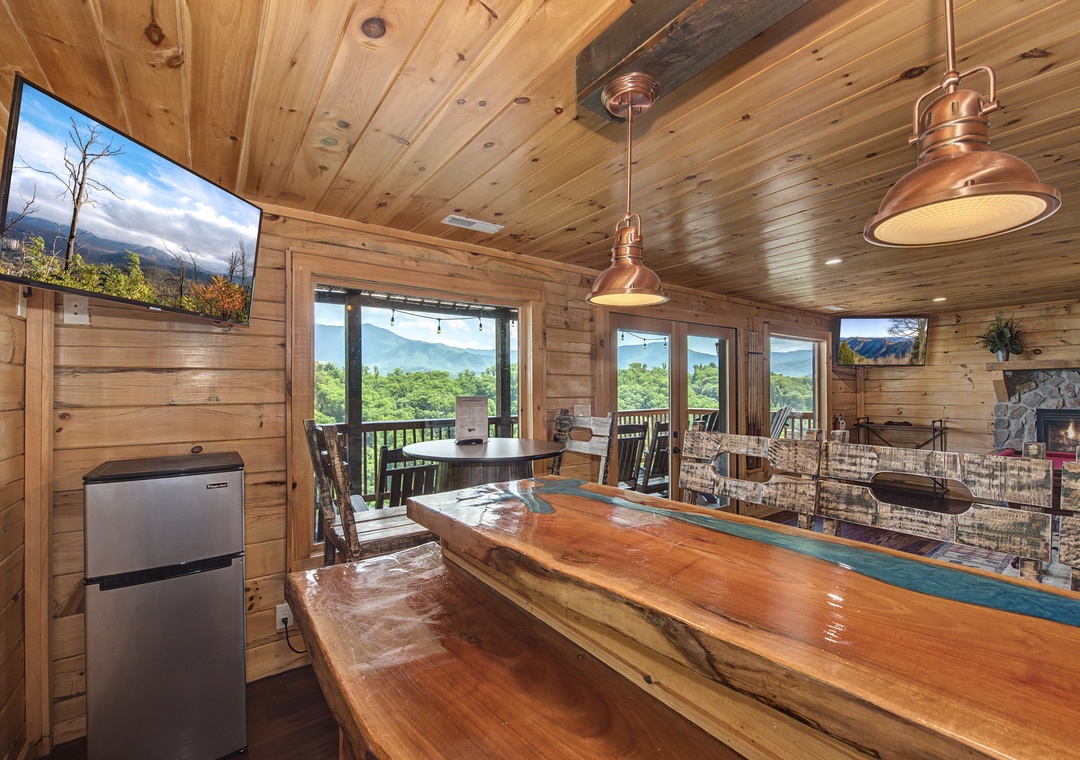 Step into your mountain retreat where a handcrafted live-edge bar invites you to unwind beneath soaring wood ceilings and copper pendant lights. Picture yourself savoring the stunning valley views framed by floor-to-ceiling windows.