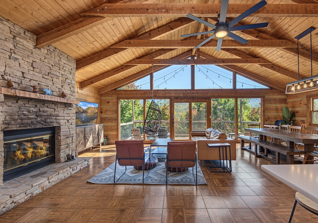 Unwind in your sun-drenched living room with soaring vaulted ceilings, warm wood tones, and a cozy stone fireplace. The open-concept layout connects seamlessly to a deck overlooking lush treetops, perfect for morning coffee or starlit evenings.
