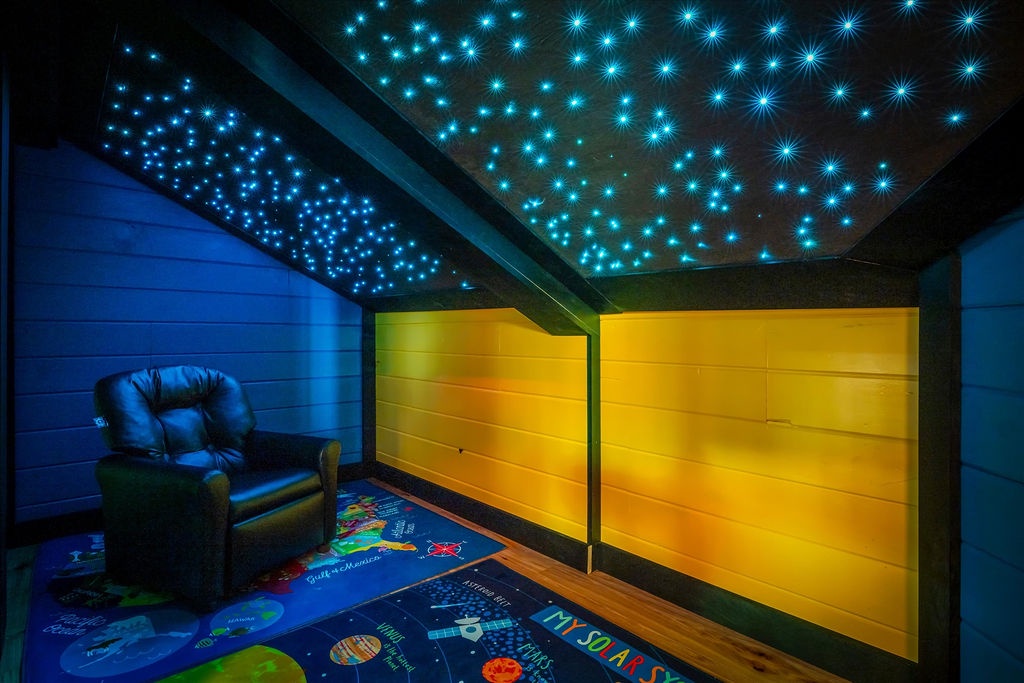 Drift into dreams under a starlit ceiling in this enchanting themed bedroom, where ambient fiber-optic stars and warm glowing panels create a magical atmosphere for your little ones.