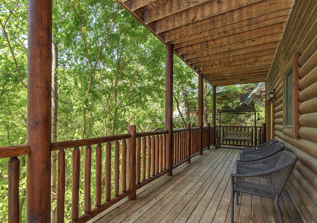 Relax on your private covered deck surrounded by lush trees, where comfortable wicker chairs invite morning coffee moments and peaceful forest views.