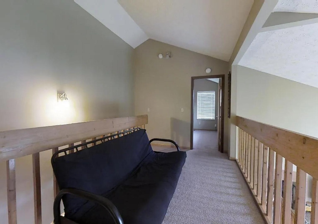 A bright loft space with vaulted ceilings and natural light, featuring a cozy futon and easy access to the next room—perfect for extra guests or peaceful retreat.