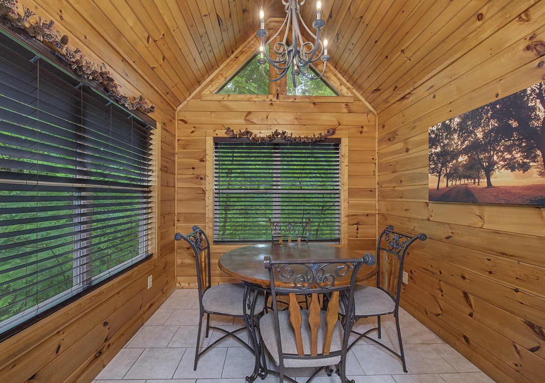 A sunlit dining nook surrounded by warm knotty pine and large windows frames your morning coffee spot, where nature meets cozy charm beneath vaulted ceilings.
