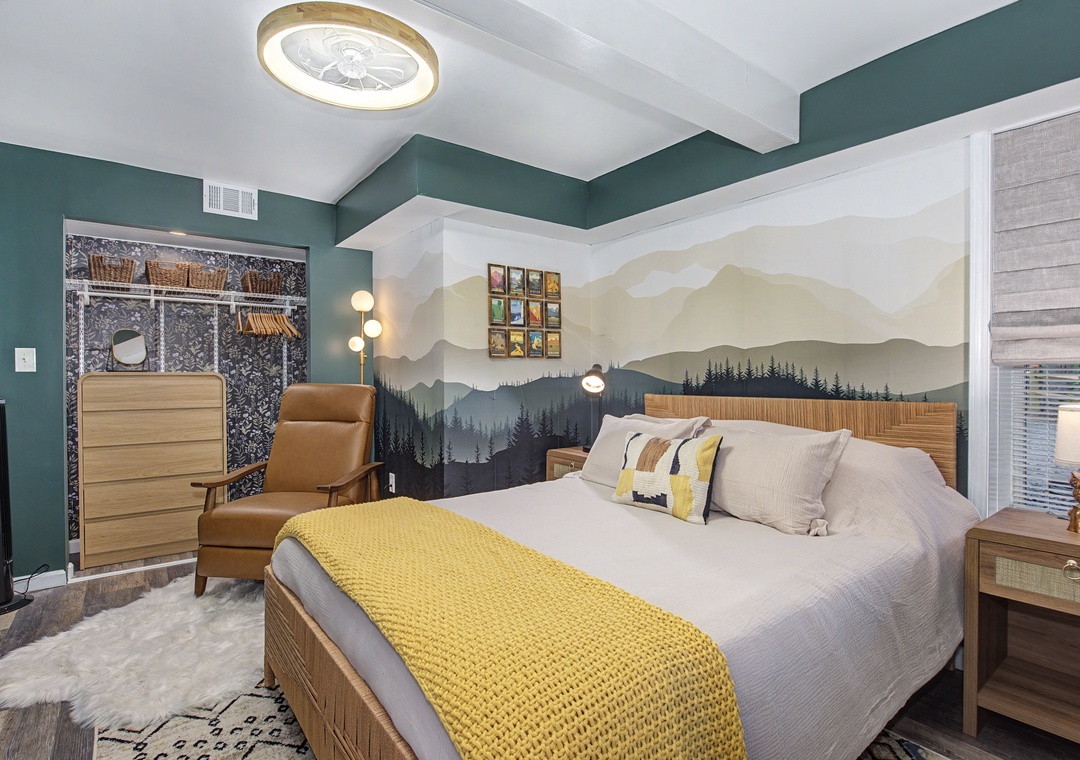 Sink into plush bedding under soaring vaulted ceilings, where a stunning mountain mural and natural wood tones create your peaceful retreat. The cozy armchair invites you to unwind with a good book.
