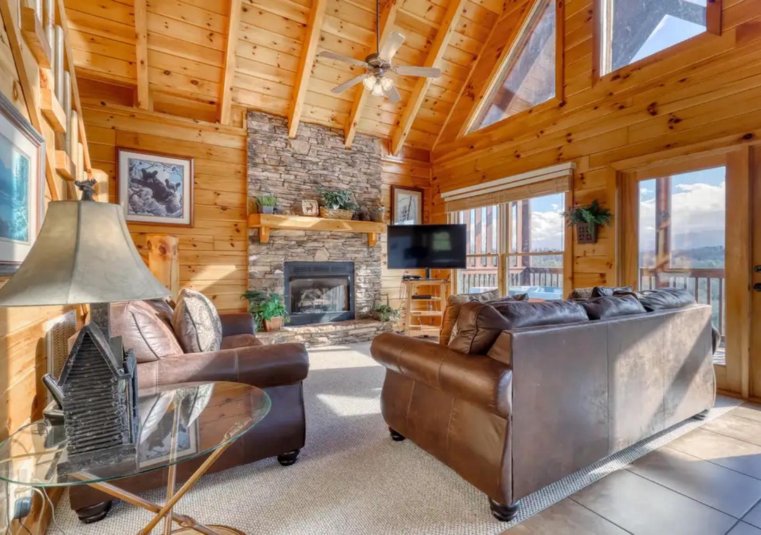 Sink into plush leather seating beneath soaring vaulted pine ceilings, where your cozy stone fireplace and panoramic mountain views create the ultimate retreat.