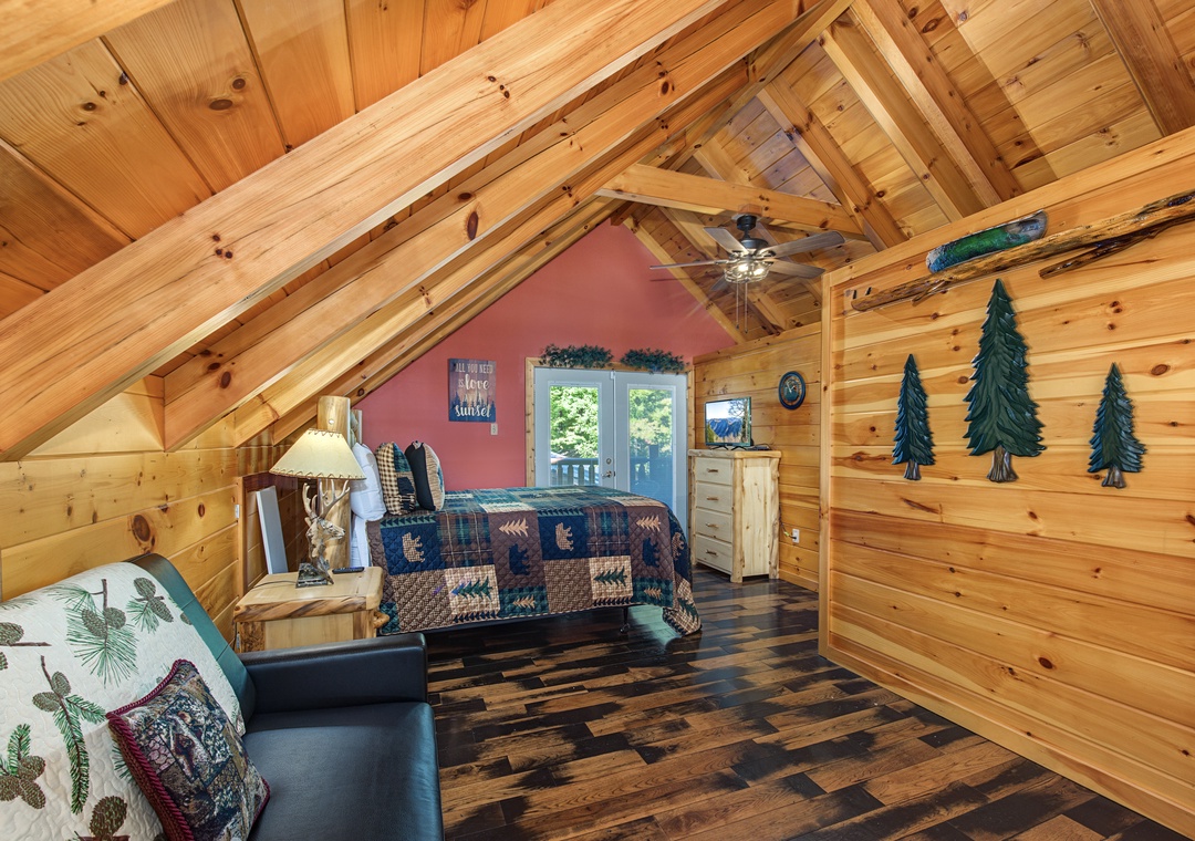 Step into your cozy cabin loft bedroom, where warm wood surrounds you and tall vaulted ceilings make the space feel airy. Your rustic retreat awaits beneath handcrafted timber beams, with natural light streaming through the windows.