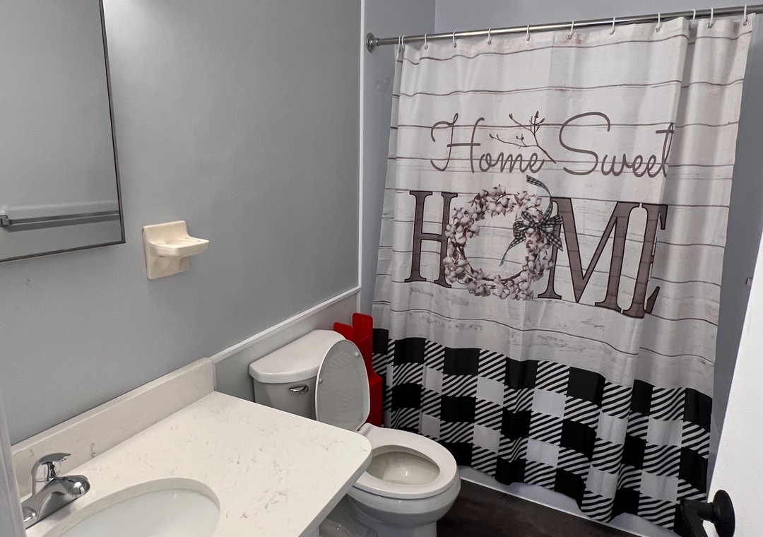 Your private bathroom features modern comfort with charming farmhouse touches, from the welcoming 'Home Sweet Home' shower curtain to gleaming fixtures.