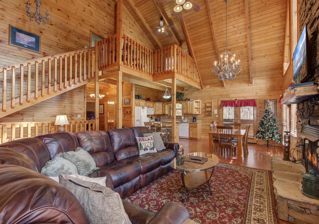 Relax in your spacious cabin's warm living room with vaulted ceilings, leather seating, and a crackling fireplace for cozy mountain evenings.