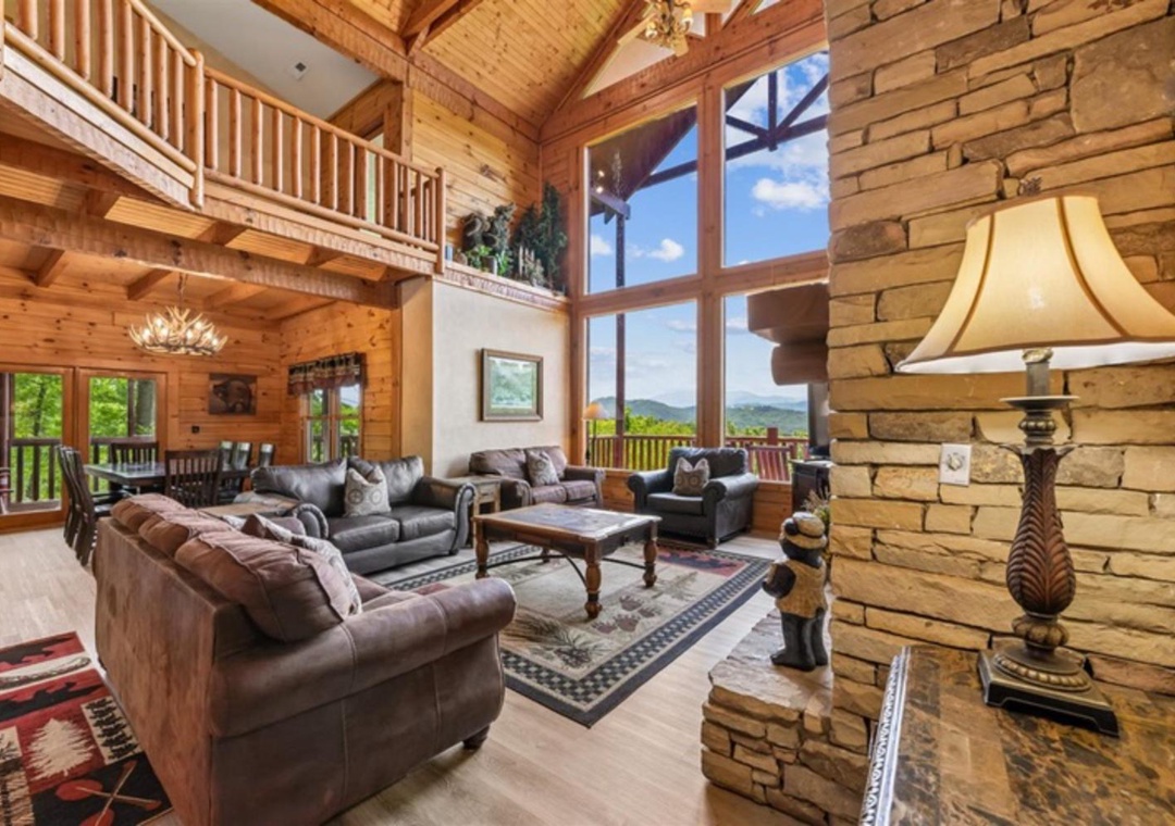 Imagine yourself in this stunning mountain cabin with soaring ceilings, where warm wood tones embrace plush seating, a stone fireplace glows, and towering windows frame breathtaking mountain views you'll wake to daily.