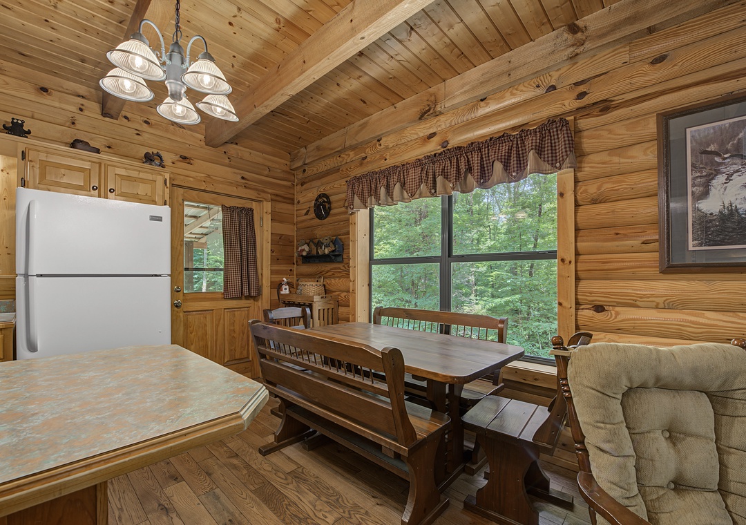 Gather around the solid wood dining table with forest views framing your meals. The cozy cabin atmosphere, complete with rustic charm and modern amenities, makes every moment feel like home.