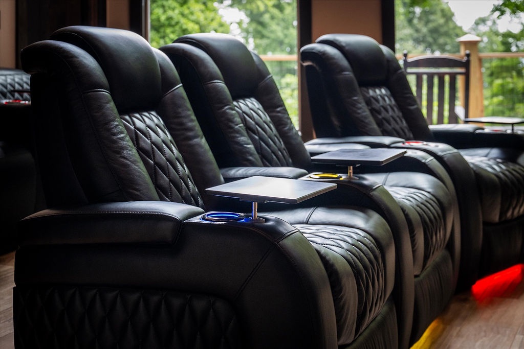 Sink into plush theater recliners and enjoy movie nights with serene forest views through floor-to-ceiling windows, your perfect indoor retreat after exploring outdoors.