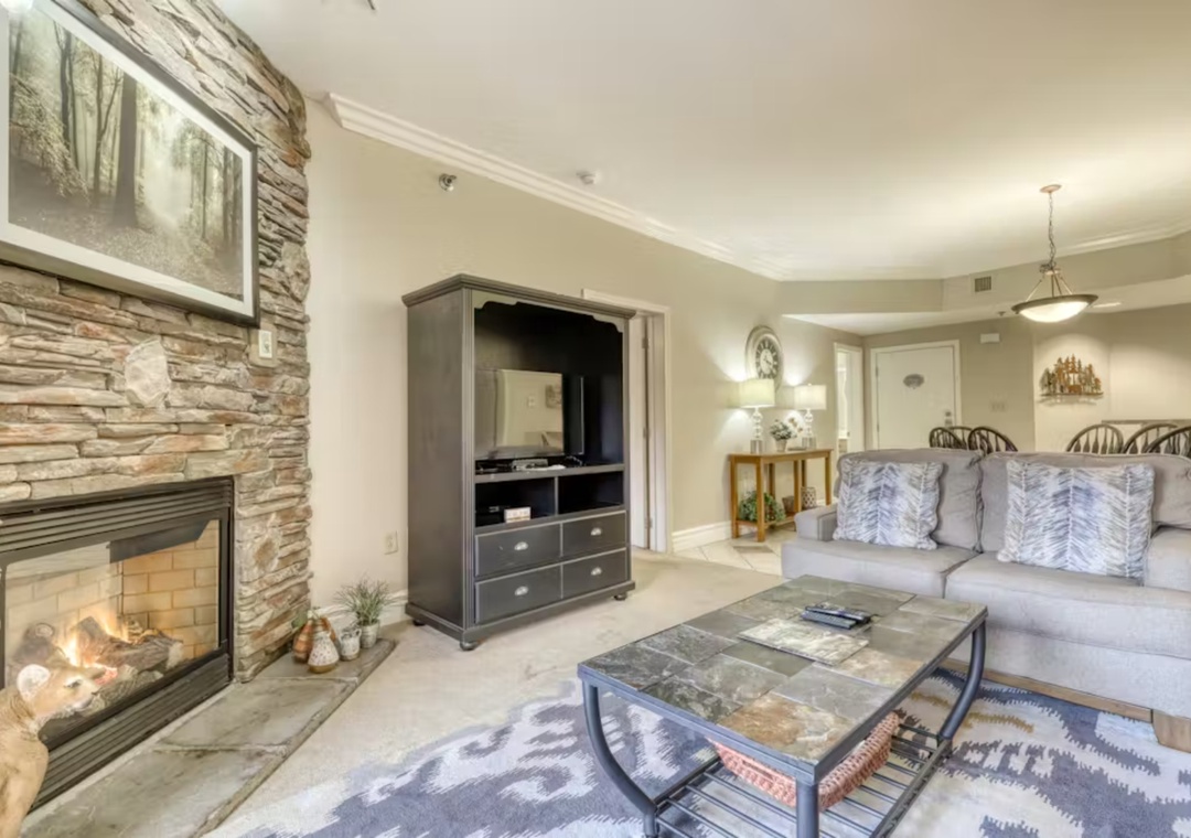 Sink into your cozy sectional sofa by the warm stone fireplace, where rustic charm meets modern comfort in your perfect mountain retreat.