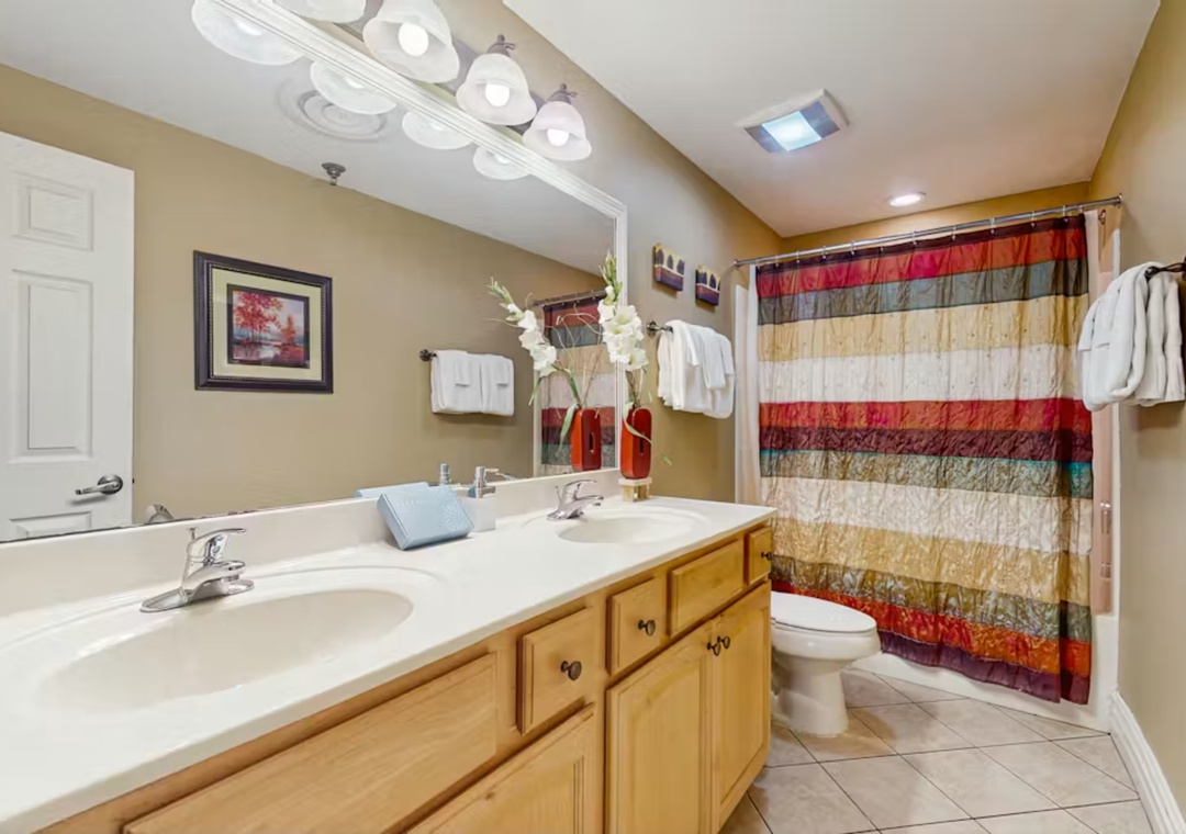Your spacious bathroom features dual vanities and vibrant décor, creating a welcoming retreat for your morning routines.