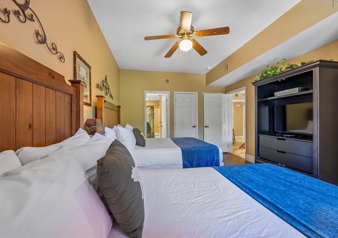 Rest peacefully in your spacious bedroom featuring two comfortable beds, warm wood accents, and modern entertainment center for cozy evenings.
