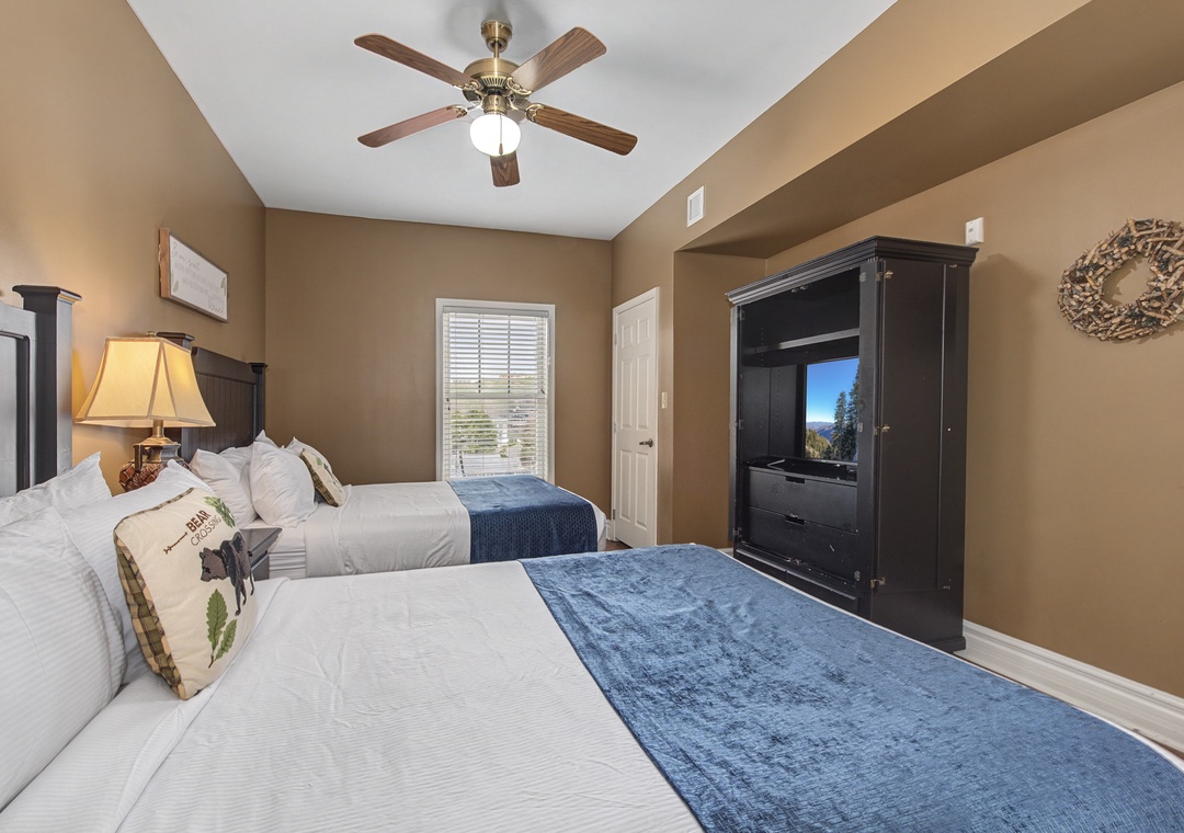 Your cozy bedroom features twin beds with soft linens, warm lighting, and entertainment center for relaxing evenings.