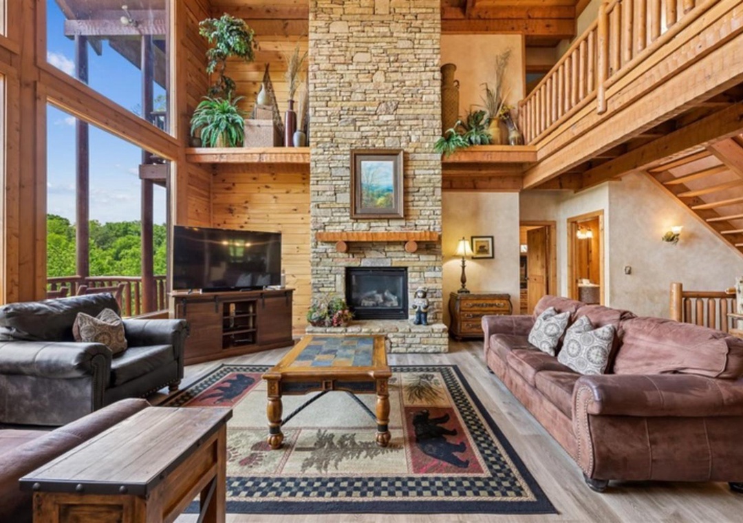Step into your inviting mountain retreat where soaring ceilings, warm wood tones, and a stunning stone fireplace create the perfect backdrop for relaxing evenings with forest views.