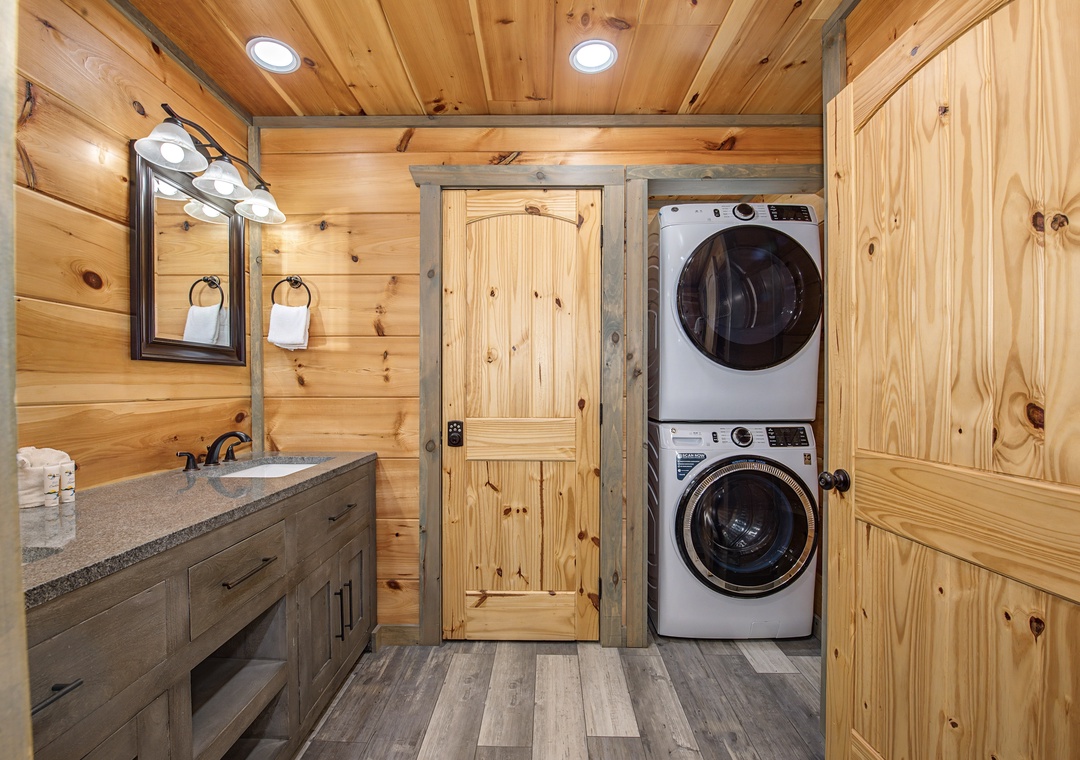 Rustic wood finishes surround you in this combined laundry and bath space. Convenient stacked washer and dryer, wardrobe storage, and a vanity with crisp towels await your arrival.