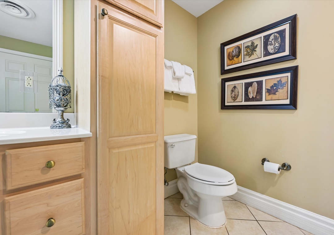 Enjoy your private bathroom with elegant warmth—natural wood cabinetry, botanical artwork, and fluffy towels create a welcoming space for your daily routines.