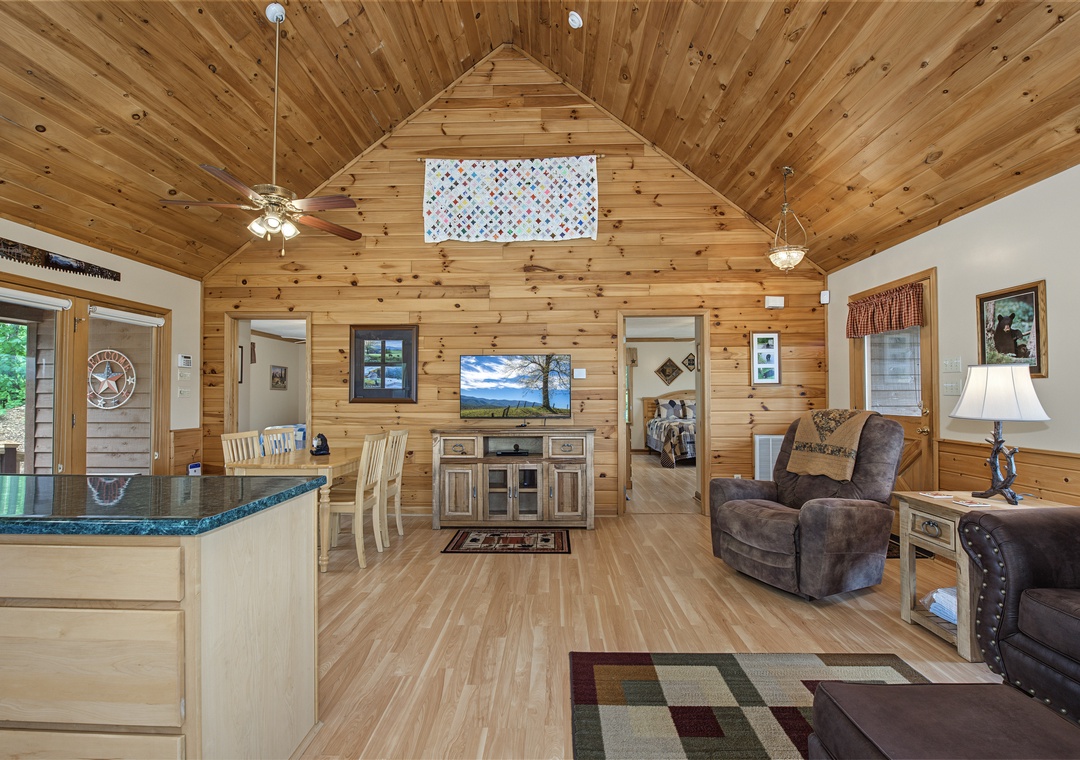 Settle into your cozy cabin retreat with soaring wood ceilings, comfortable seating, and an open layout connecting your living space to the kitchen and bedrooms beyond.