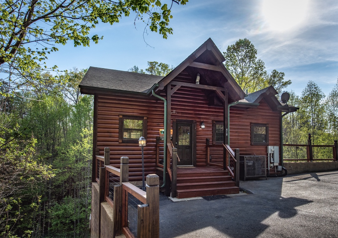 Rustic log cabin nestled among towering trees, featuring classic mountain architecture and convenient paved access for easy arrival.