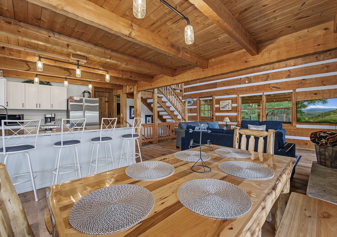 Gather around the handcrafted dining table and soak in mountain views through expansive windows. This open-concept retreat blends rustic wood beams with modern comforts, perfect for memorable meals and cozy evenings together.