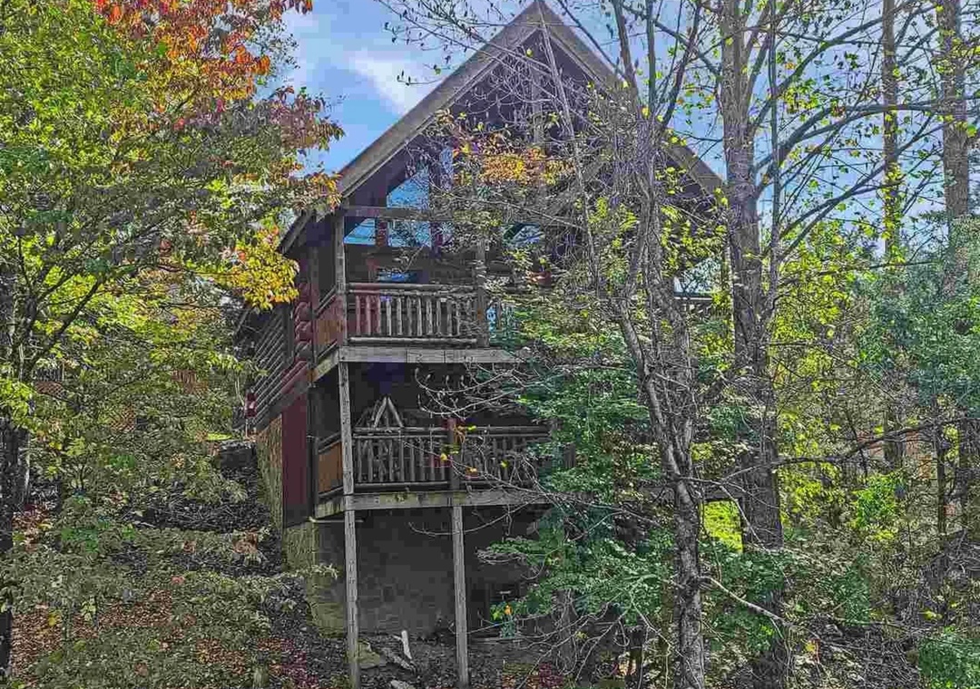 A rustic mountain cabin nestled among vibrant autumn foliage, featuring wooden balconies and natural forest surroundings.