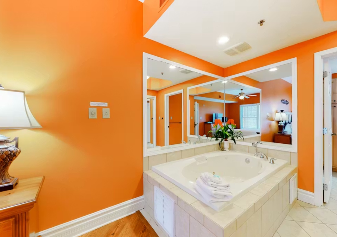 Soak away your stress in this luxurious jetted tub surrounded by vibrant orange walls and elegant mirrors.