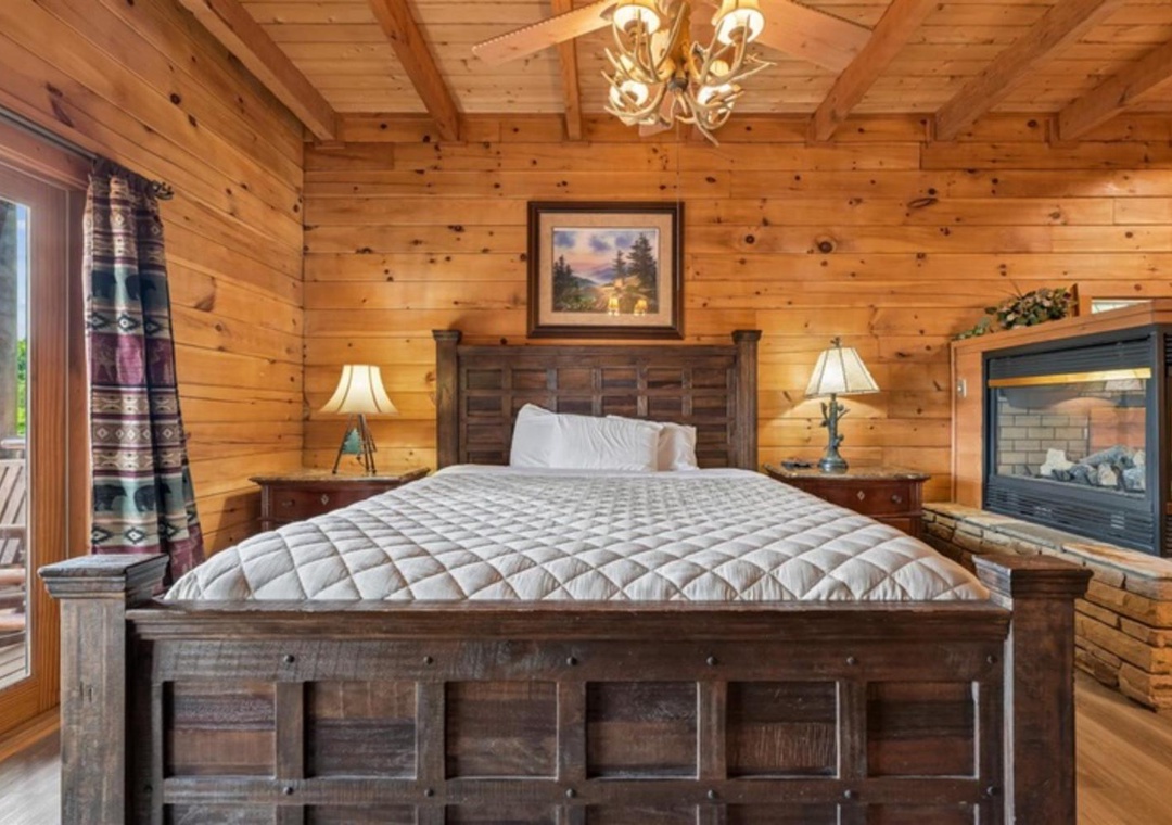 Drift off in your cozy bedroom, where rustic wood walls meet plush comfort. The antler chandelier and warm fireplace create a perfect retreat after your mountain adventures.