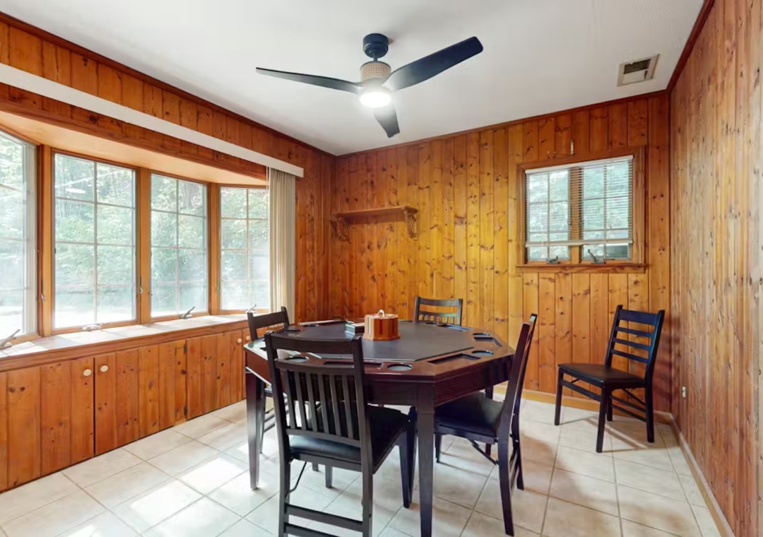 Gather around this cozy wood-paneled dining space where natural light streams through large windows, creating the perfect atmosphere for your meals together.