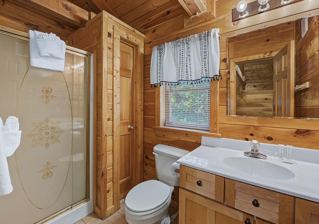 This cozy cabin bathroom brings rustic comfort to your mountain retreat with warm wood walls and thoughtful touches like fresh towels and natural light.