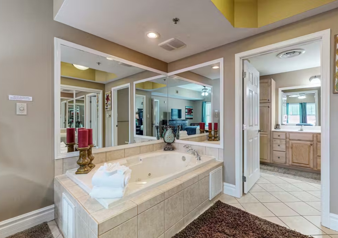 Unwind in your private spa-like bathroom featuring a luxurious jetted tub surrounded by elegant mirrors, perfect for soaking away the day.