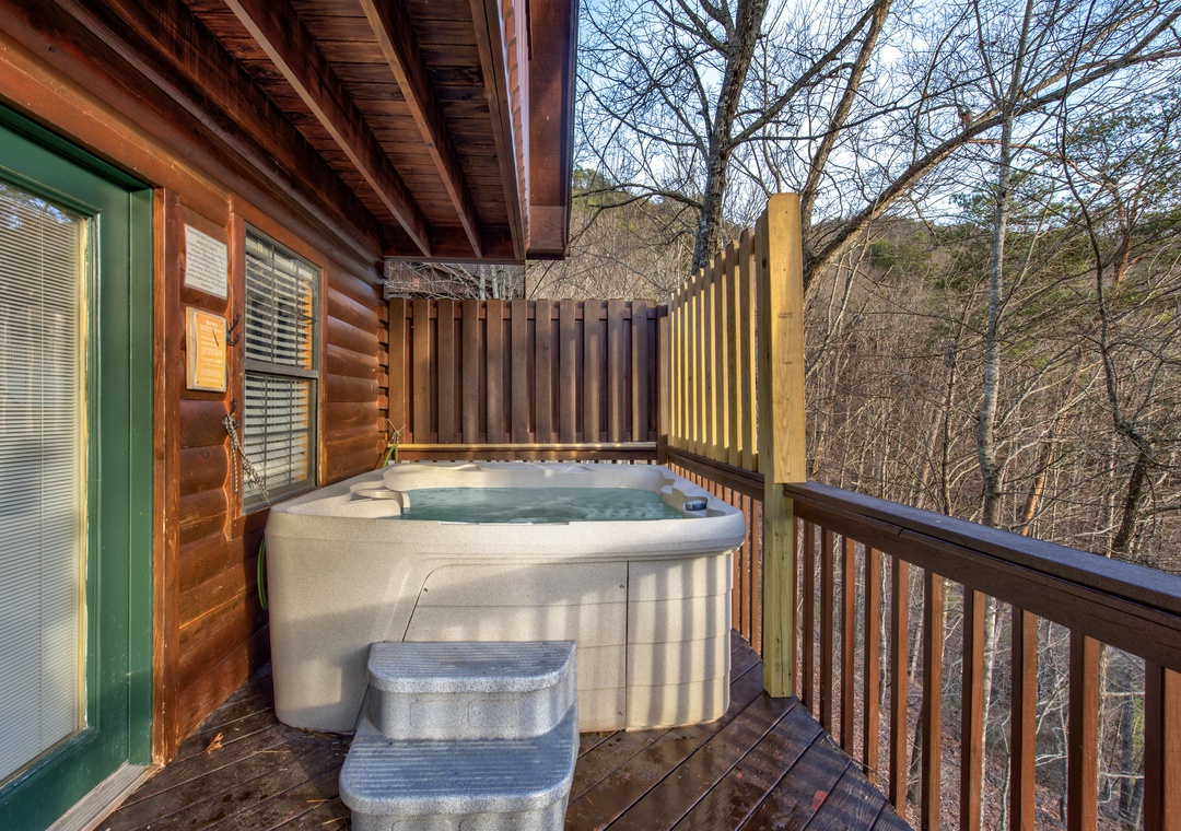 Soak in your private hot tub surrounded by peaceful forest views from this secluded wooden deck.